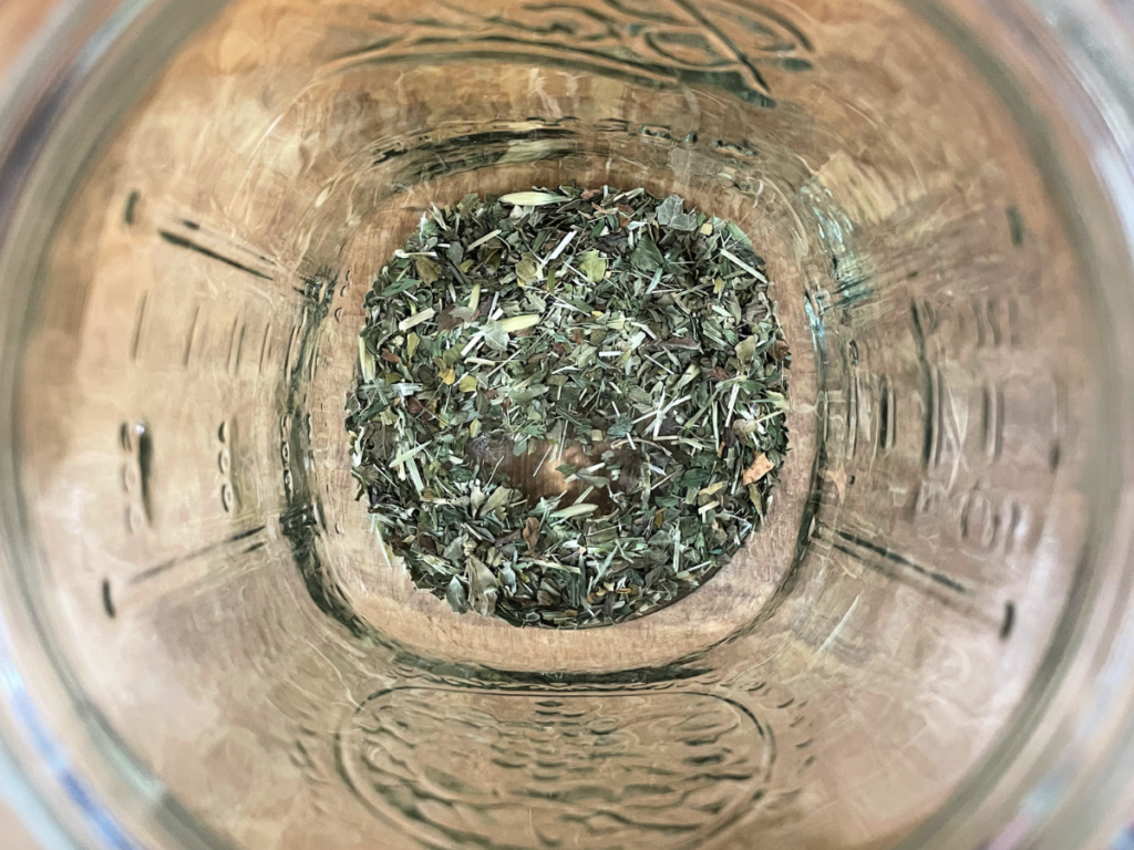 Picture of tea leaves in a jar on a wooden counter.