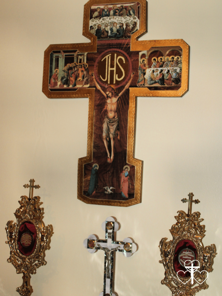 Picture of two crucifixes with two reliquaries by their side against a cream wall.