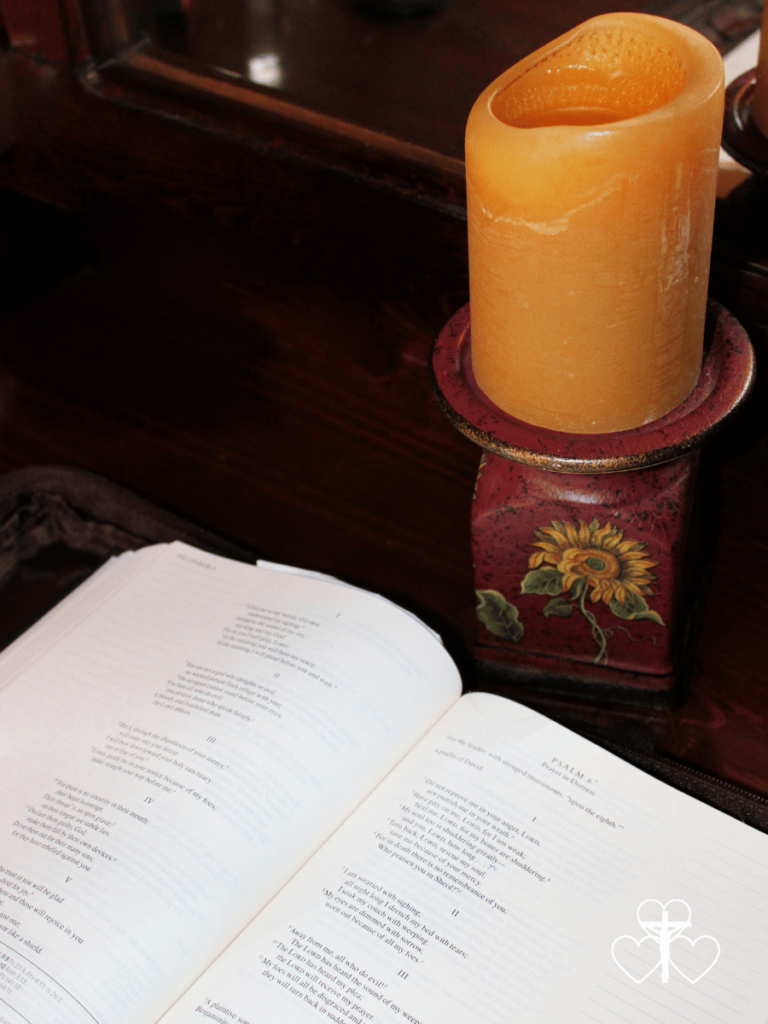 Picture of an open bible and candle on a sunflower pedestal.